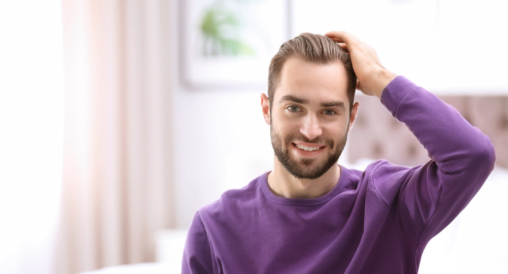 Man with hair transplant combing his hair by hand